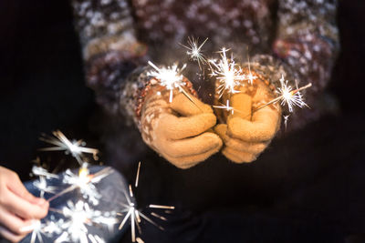 Midsection of woman holding sparkler at night