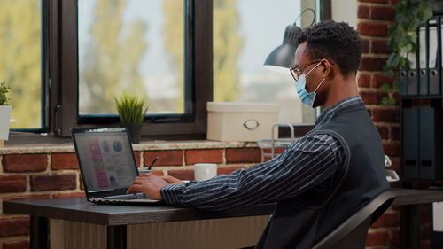 Side view of businessman using laptop at office