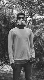 Full length portrait of young man standing against trees in forest