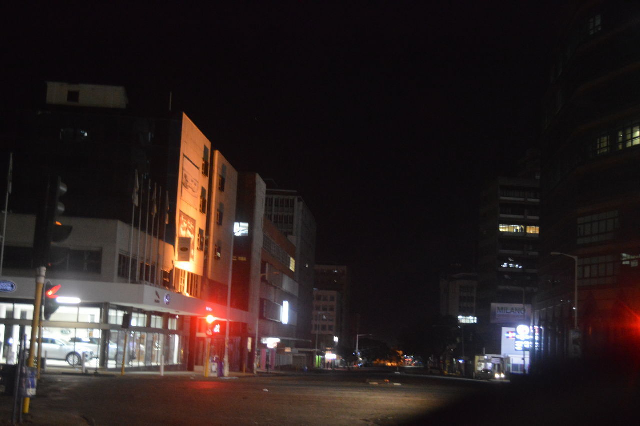 STREET AMIDST BUILDINGS AT NIGHT