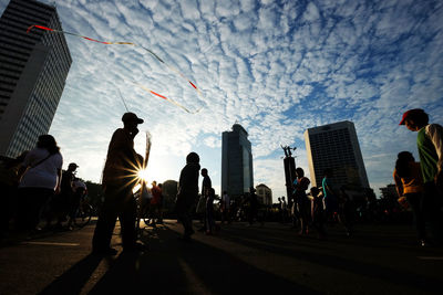 People on street against sky during sunset