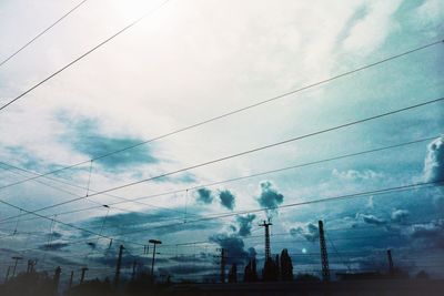 Low angle view of electricity pylon against cloudy sky