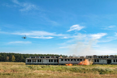 Airplane flying over train against sky