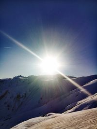 Scenic view of snowcapped mountains against sky on sunny day
