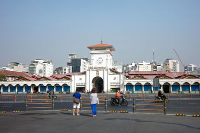 A tourist couple is standing and visiting in front of ben thanh market