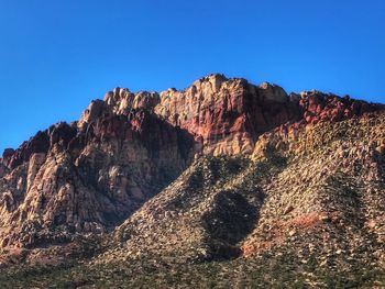 Low angle view of cliff against clear blue sky