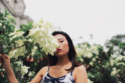 Portrait of a beautiful young woman against white flowering plants