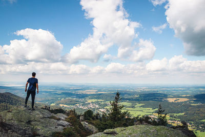 Standing on a high rock in jizera mountains, the young man enjoys a view of liberec 