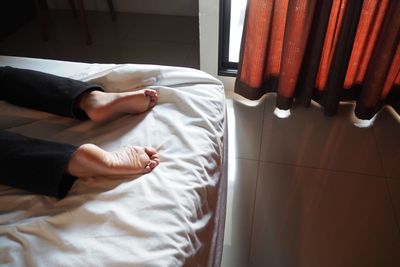 Low section of woman relaxing on bed at home