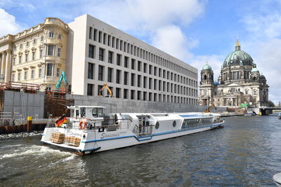 Boats in canal by buildings against sky