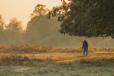 Man walking with dog on field during sunset