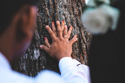 Midsection of man touching tree trunk