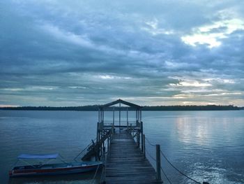 Pier on sea against cloudy sky