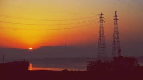 Silhouette electricity pylon against sky during sunset