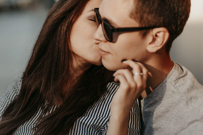 Close-up of beautiful woman kissing boyfriend in city during sunset