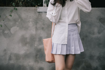 Midsection of woman standing against white wall