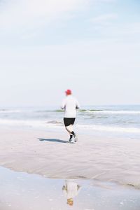 Rear view of man on beach against sky