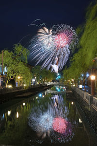 Firework display over illuminated city against sky at night