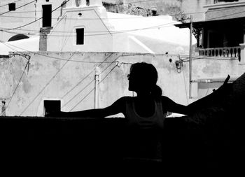 Rear view of girl on building against sky