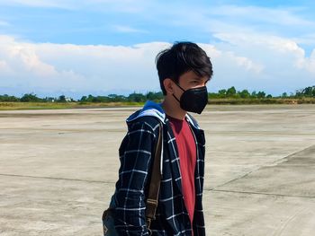 Rear view of asian boy standing at field wearing a mask