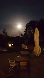 Empty chairs and table against sky at night