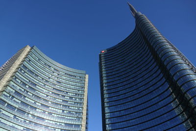 Low angle view of skyscrapers against clear blue sky