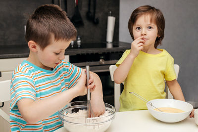 Two brothers prepare cake dough in the kitchen at home. time with children at home. 