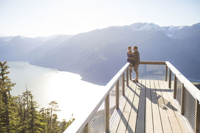 Couple looking face to face against mountains at observation point during sunny day