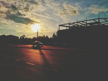 Cars on road against sky during sunset