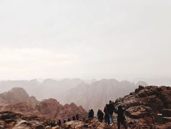 People on rocks against mountain range