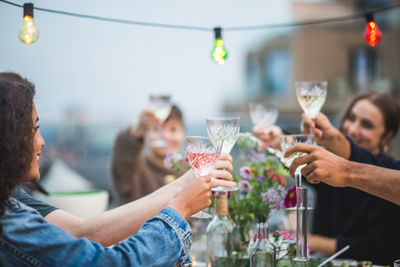 Young friends toasting drinks during social gathering on building terrace