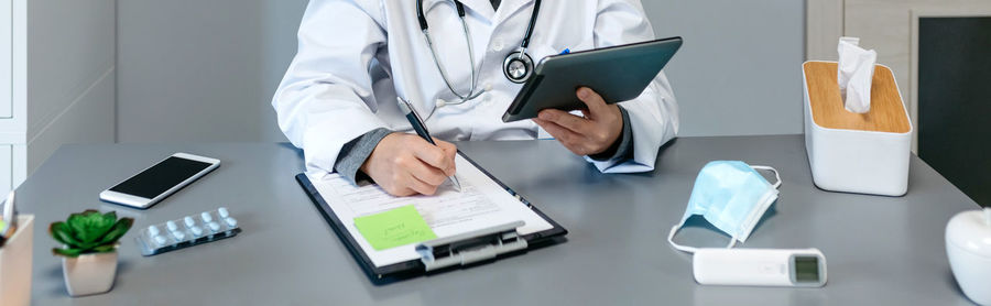 Midsection of man using smart phone on table
