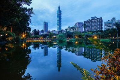 Reflection of illuminated buildings in city against sky