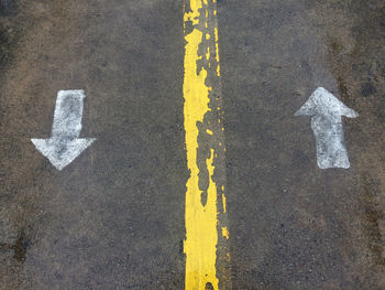 High angle view of arrow symbols on wet road during rainy season