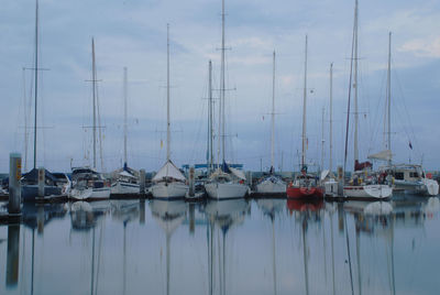 Sailboats moored on sea against sky