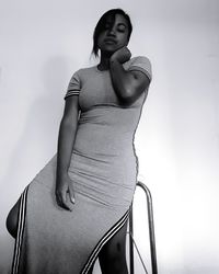 Young woman sitting on seat against wall