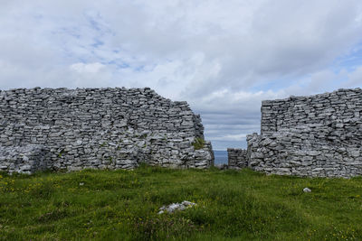 Stone wall on field against sky