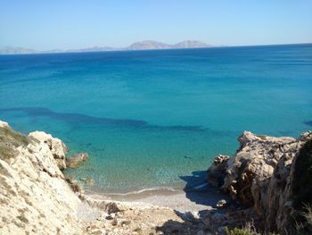 Scenic view of sea and hill against sky