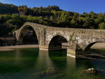 Arch bridge over river against sky