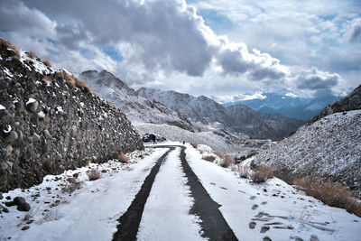 Road amidst snow covered mountains against sky