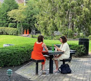 Woman sitting on bench against plants