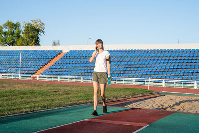 Full length portrait of young woman standing on swimming pool