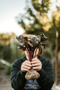 Midsection of woman holding beet in field