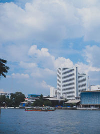 Sea by modern buildings against sky in city