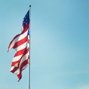 Low angle view of flag against clear blue sky