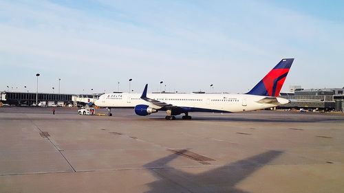 Airplane on airport runway against sky