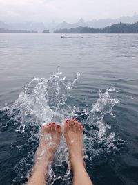 Low section of woman splashing water in sea