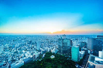 High angle view of illuminated city buildings against sky during sunset