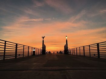 Silhouette bridge against orange sky