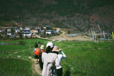 Rear view of women on pathway amidst grass